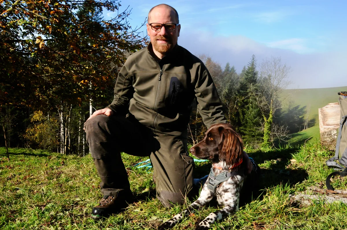 Man sieht einen Jäger mit seinem Jagdhund.